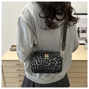 Detail of leopard print crossbody bag with dual golden zippers and black wide strap