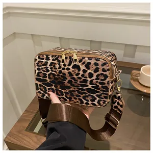Detail of leopard print crossbody bag with golden dual zippers and adjustable wide strap