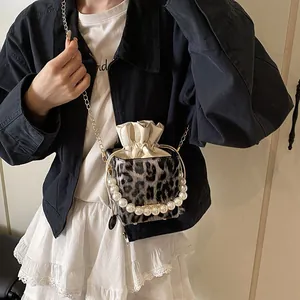 Stylish leopard print bucket bag with pearl handle and metal chain on a model