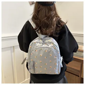 Rear view of a light blue floral backpack with multi-pocket design on a female model