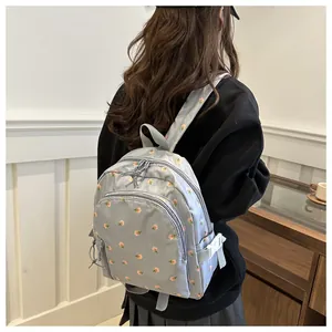 Detail of light blue mini backpack featuring pink rose floral print and zippered front pocket
