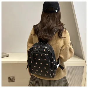 Detail of cute black mini backpack with pink floral prints worn by a model