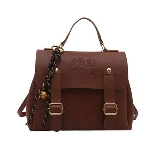 Retro-Damenrucksack aus braunem Leder mit Metallschnallen und geflochtenem Glockenanhänger
