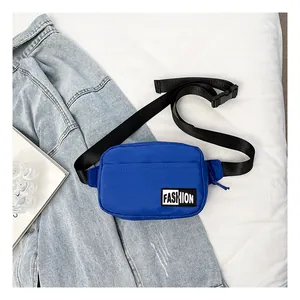 Detail of bright blue nylon crossbody bag with black adjustable strap and FASHION label
