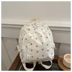 Detail showing cream floral mini backpack with adjustable straps on a wooden table
