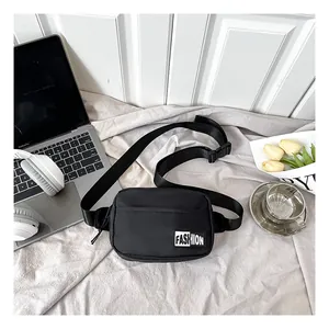 Detail of black nylon crossbody waist bag with Fashion label on grey textured surface