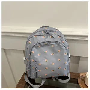 Close-up of blue floral backpack with waterproof fabric and multi-zipper pocket detail