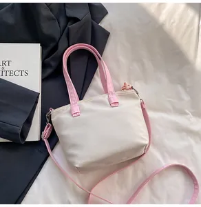Détail du sac seau en nylon crème avec poignées roses et boucles de réglage en métal argenté