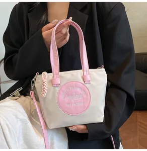Détails des poignées en similicuir rose et bandoulière sur sac seau en nylon blanc