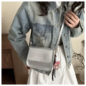 Detail of silver metallic square bag with pink bear print and plush bear charm