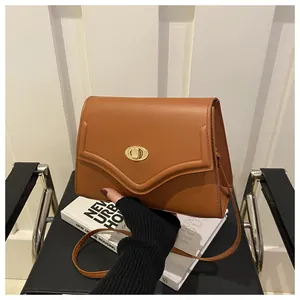 Dettaglio borsa marrone con patta a V e chiusura girevole dorata su una sedia