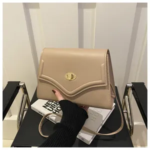 Dettaglio borsa a tracolla beige con chiusura a scatto dorata e goffratura a V