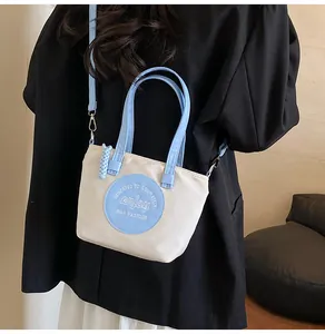 Détail d'un sac seau en nylon avec poignées bleu ciel et patch logo Enjoy brodé