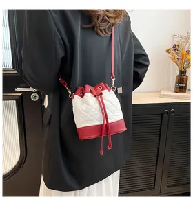 Detail of quilted stitching on a contrast bucket bag with red drawstring and gold hardware
