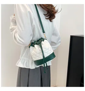 Close-up of quilted bucket bag featuring white diamond pattern and dark green contrast trim