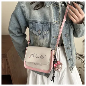 Close-up of pink crossbody bag with cartoon bear prints and a plush teddy charm detail
