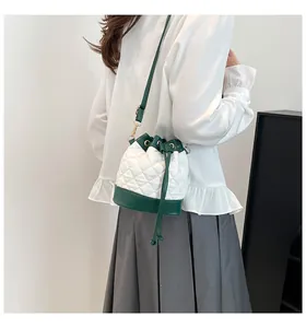 Quilted drawstring bucket bag in white and green leather worn by a model