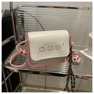 Detail of a pink and white crossbody bag with cute puppy prints and a soft plush pendant