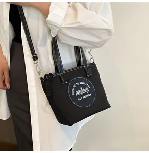 Détail du sac seau en nylon noir avec logo blanc et surpiqûres contrastées pour femme