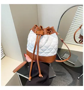 Close-up of a quilted color-block bucket bag with brown drawstring and white leather texture