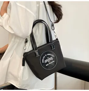 Détail du sac seau en nylon noir avec poignées en cuir et breloque décorative en corde