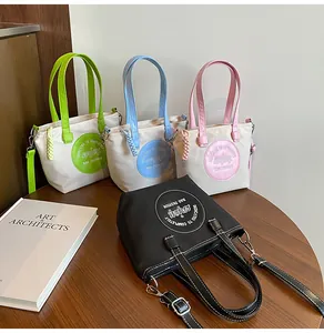 Vue détaillée de sacs seaux en nylon colorés avec bandoulières sur une table en bois