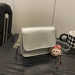 Metallic silver crossbody square bag with pink cartoon bear and plush character charm