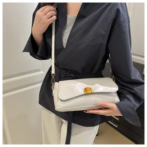 Détail du sac carré crème en cuir verni brillant avec fermoir métallique doré chic