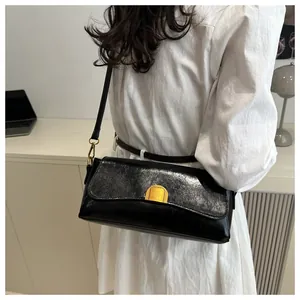 Détail d'un sac à bandoulière noir rétro en cuir brillant avec fermoir doré élégant