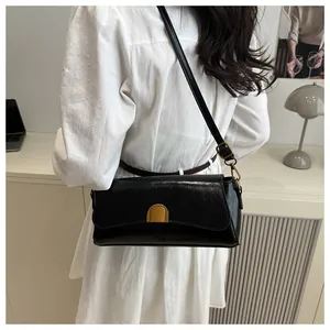Détail d'un sac à bandoulière rectangulaire noir avec boucle dorée sur un mannequin