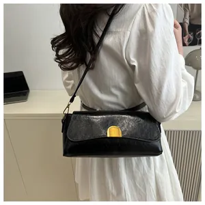 Détail d'un sac à bandoulière noir en cuir huilé synthétique avec boucle dorée demi-cercle