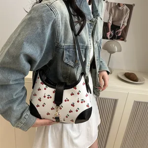 Chic white crescent shoulder bag with red cherry print and black leather accents