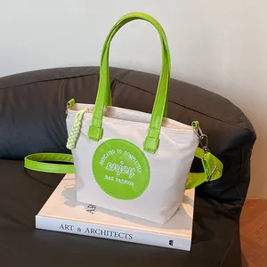 Sac seau en nylon blanc cassé avec bordure en PU vert et bandoulière réglable pratique