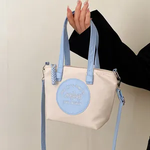 Sac seau en nylon contrasté crème et bleu avec bandoulière réglable et poignée