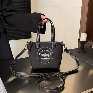 Sac seau noir en nylon avec surpiqûres blanches et bandoulière réglable amovible