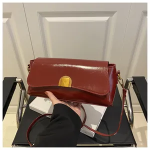 Détail du sac à bandoulière rouge foncé brillant avec boucle métallique dorée chic