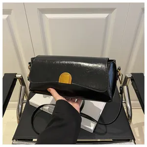Détail d'un sac à bandoulière en cuir PU brillant noir avec fermoir métallique doré