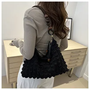 Détail du sac noir en tissu texturé popcorn avec perles décoratives en bois marron foncé