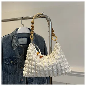 Détail du sac blanc en tissu gaufré avec bandoulière en perles de bois et anneaux