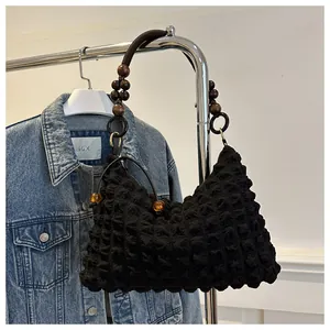 Détail du sac en tissu gaufré noir avec bandoulière en perles de bois et breloques