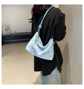 Détail du sac bandoulière bleu clair avec lignes ondulées brodées colorées sur le tissu