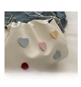 Détail du sac nuage plissé blanc avec écussons cœur colorés et bandoulière chaîne