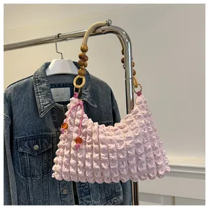 Détail du sac plissé rose en seersucker avec anse en corde tressée et perles en bois