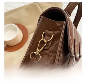 Detail der dunkelbraunen Satchel-Tasche mit hochwertigen goldenen Metallhaken und D-Ringen