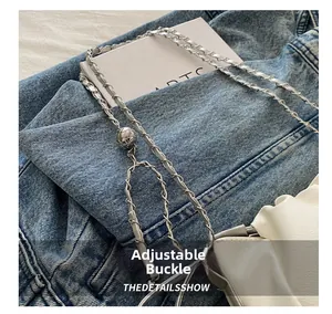 Détail de la chaîne argentée avec boucle réglable sphérique sur sac blanc plissé