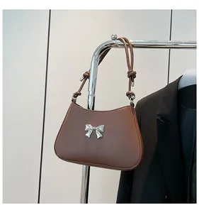 Détail d'un sac porté épaule en cuir marron avec nœud métallique argenté et sangle