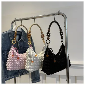Détail du tissu gaufré avec poignée en perles de bois et gland latéral sur le sac
