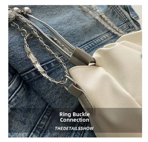 Détail du raccord à boucle et de la chaîne en métal argenté sur le sac seau en cuir blanc
