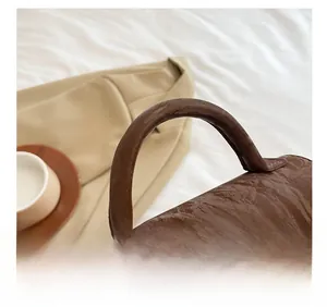 Detail der karamellbraunen Handtasche aus Faltenleder mit robustem Rundgriff-Design