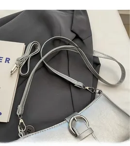 Detail of silver crossbody bag with metallic texture, thin leather strap and metal buckle